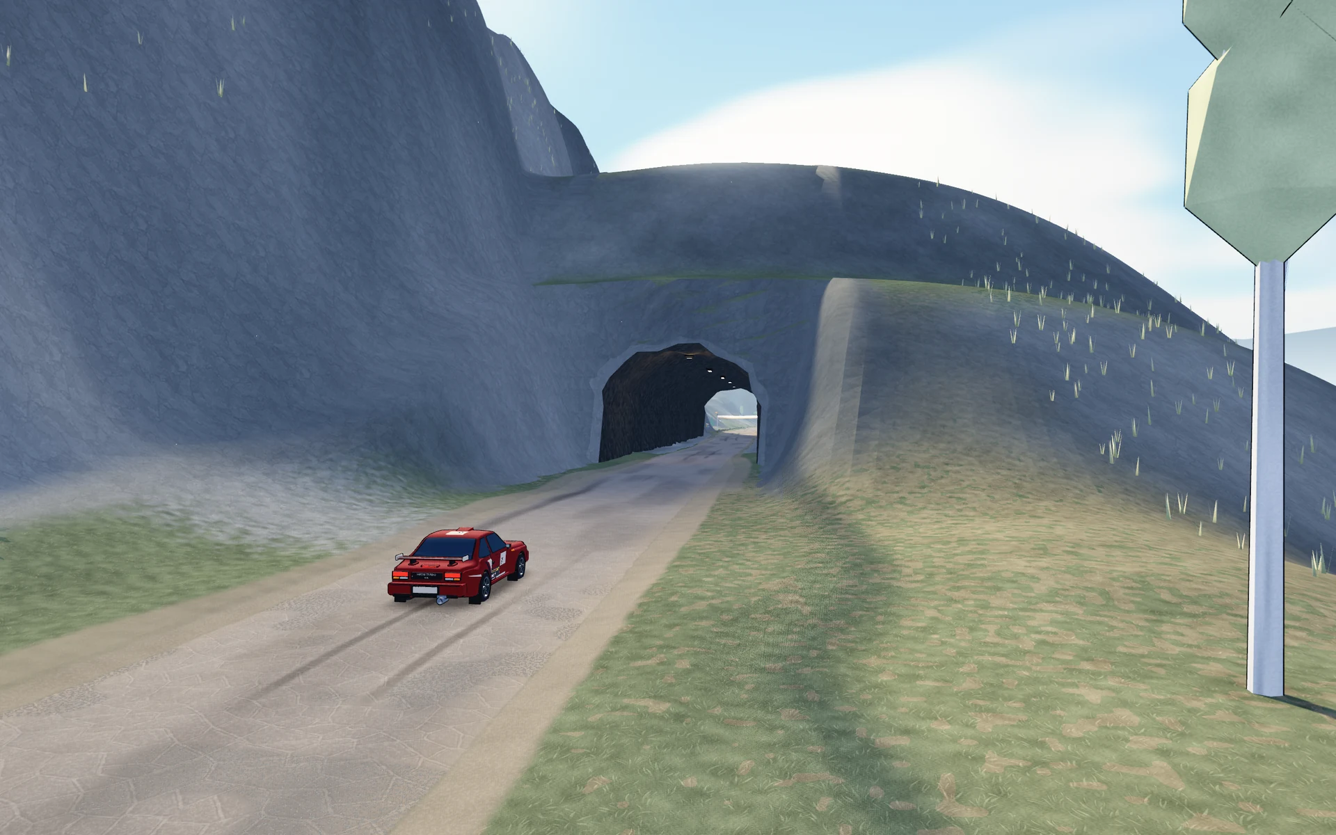 The red Hayai Turbo beside a rough-cut tunnel through a rocky mountainside.